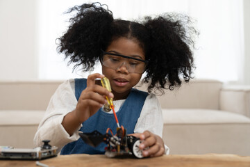 Wall Mural - Child girl learning toy robotics technology online with computer tablet. Adorable young girl building robotic toy car in classroom at school. Education and technology concept