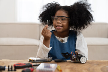 Wall Mural - Child girl learning toy robotics technology online with computer tablet. Adorable young girl building robotic toy car in classroom at school. Education and technology concept