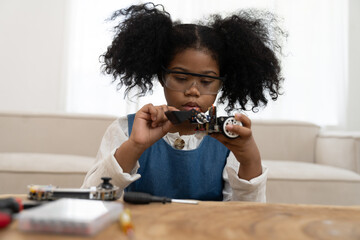 Wall Mural - Child girl learning toy robotics technology online with computer tablet. Adorable young girl building robotic toy car in classroom at school. Education and technology concept