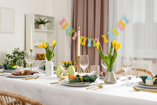 Wall Mural - Festive Easter table setting with painted eggs, burning candles and yellow tulips in room