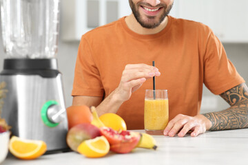 Poster - Man with delicious smoothie at white marble table in kitchen, closeup