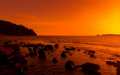 Wall Mural - Ocean orange sunset landscape with rocks in silhouette