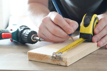 Carpenter hand measuring tape with pen in construction site. Making measurements with measuring tape and making marks with pen.