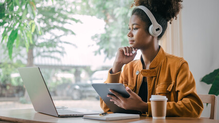 Wall Mural - Using headphones. Young african american university foreign exchange students study online on laptop pc english language class by international specialists with master at cafe.