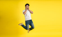 Full Length Image Of Young Asian Man On Yellow Background