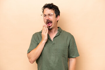 Wall Mural - Young caucasian man isolated on beige background yawning and covering wide open mouth with hand