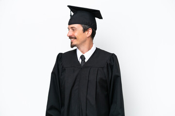 Wall Mural - Young university graduate man isolated on white background looking side