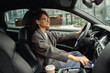 © Kostiantyn - Attractive woman driving car in city with one hand on steering wheel and another on gear lever