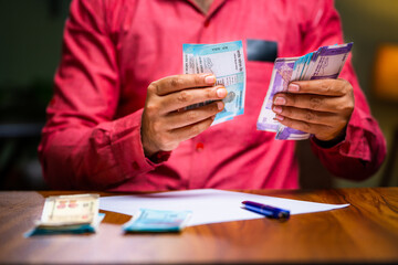 close up shot of Middle aged family man hands doing monthly budget calculation at home - concept of middle class lifestyle, savings and expenses planning.