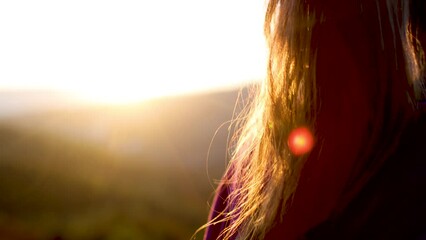 Wall Mural - A woman with long wavy hair looks at the sunset. back view. sunset light