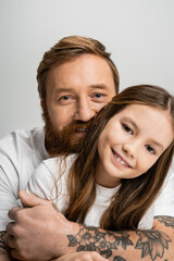 Wall Mural - Portrait of smiling parent hugging preteen daughter isolated on grey.