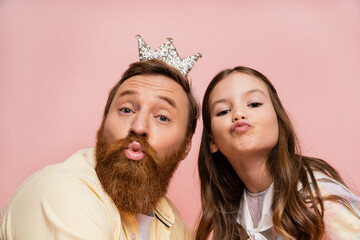 Poster - Bearded dad with crown headband pouting lips near daughter isolated on pink.