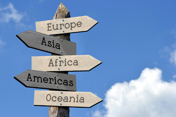 Canvas Print - Europe, Asia, Africa, Americas, Oceania - wooden signpost with five arrows, sky with clouds