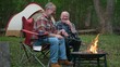 © Robert Peak - Closeup of two gay men in front of campfire laughing and smiling celebrating pride.