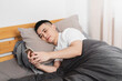 © Anciens - Asian man is lying in the bed using mobile phone.