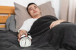 © Anciens - Asian man is unwilling to close the alarm clock in the morning.