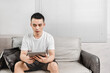 © Anciens - Asian man is using digital tablet on the sofa.