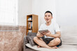 © Anciens - 亚洲男青年坐在沙发上看平板电脑