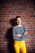 © Cavan Images - Portrait of happy businesswoman standing arms crossed against brick wall