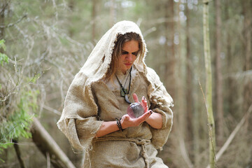 Canvas Print - A man in a cassock spends a ritual in a dark forest