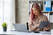 © crizzystudio - Portrait of a young Asian businesswoman working on a tablet with a laptop at the thinking office. analyze marketing data online business ideas.