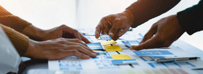 A group of Asian UI developers, designers, and data researchers are brainstorming their projects with laptops, smartphones, and digital tablets. Creative Digital Development Agency.
