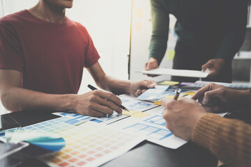 ux developers, UI designers Asian group data researchers brainstorm on tabletop mobile app interface wireframe design client summary color codes modern office Creative Digital Development Agency.