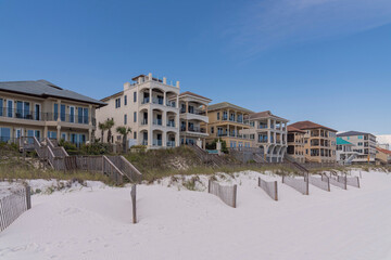 Canvas Print - Multi-storey beach houses against clear blue sky in Destin Florida. Coastal landscape with waterfront homes overlooking the sandy shore and ocean.