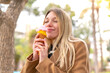 © luismolinero - Young pretty blonde woman with a cornet ice cream at outdoors