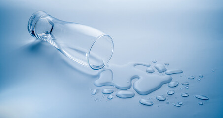 glass water spilled, drops of water spill on light blue background, copy space