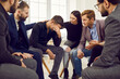 © Studio Romantic - Bad news. View of the group of businessmen comforting their frustrated colleague. Guy holds his hand near his forehead. Teammates calm down distressed colleague by putting their hand on his shoulder.
