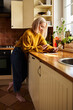 © baranq - Adult woman writing on digital tablet in a kitchen leaning on counter
