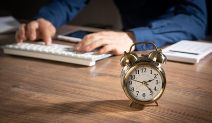 Businessman working at office with a alarm clock on the table.