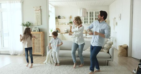 Wall Mural - Cheerful happy parents and little kids dancing jumping to music at home, laughing, enjoying energetic activity, having fun, laughing for joy, celebrating moving, warming up for exercises