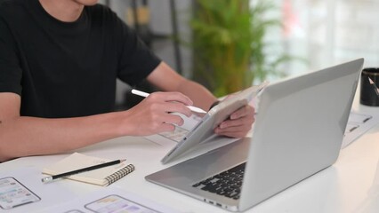 Wall Mural - Cropped shot of male website designer using digital tablet, working in a studio to create application for mobile phone