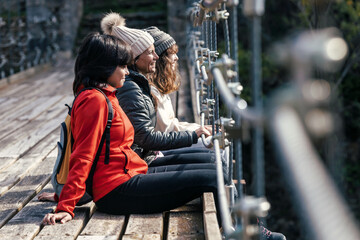 beautiful family looking forwards while sitting on a bridge in mountain forest