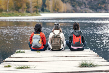 Shot of pretty family looking at the horizon sitting on a pier on the lake