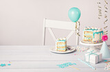 Fototapeta Tęcza - Birthday party table setting with slice of vanilla confetti cake and decorations on a light grey white background