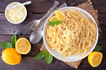 Wall Mural - Spaghetti pasta with fresh lemon and parmesan cheese sauce. Above view table scene on a dark wood background.