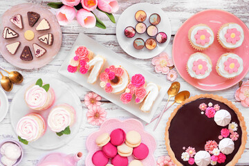 Wall Mural - Mothers Day table scene with an assortment of desserts and sweets. Overhead view on a white wood background. Pink flowers theme.