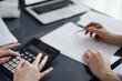 © rogerphoto - Woman accountant using a calculator and laptop computer while counting taxes for a client. Business audit and finance concepts