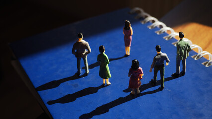 Group of miniature human figures of men and women standing on the book