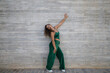 © @skuder_photographer - Latin woman, young and beautiful dancing modern dance on a background of gray cement in the street makes different expressions and postures. Concept dance, hip hop, dance, art, action, youth art.
