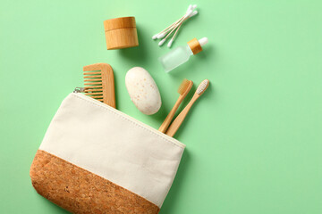 Purse with eco friendly bathroom hygiene cosmetics on green background.