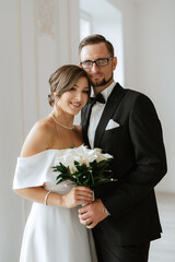 Wall Mural - groom in a black suit tie and the bride in a bright studio