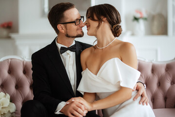 Wall Mural - groom in a black suit tie and the bride in a bright studio