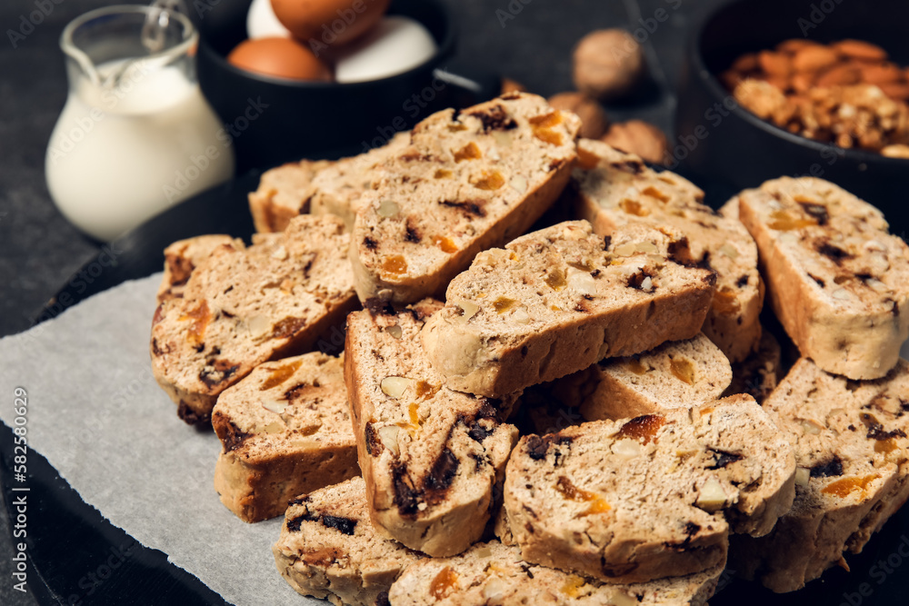 Board with delicious biscotti cookies on black grunge background