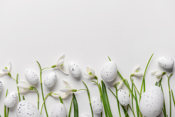 composition with easter eggs and beautiful snowdrops on light background, closeup