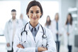 © aicandy - Portrait of a female doctor in her white coat with a stethoscope around her neck, standing in front of a medical team, generative ai
