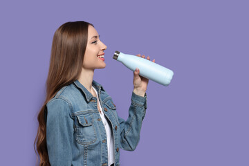 Poster - Beautiful young woman with thermos bottle on purple background